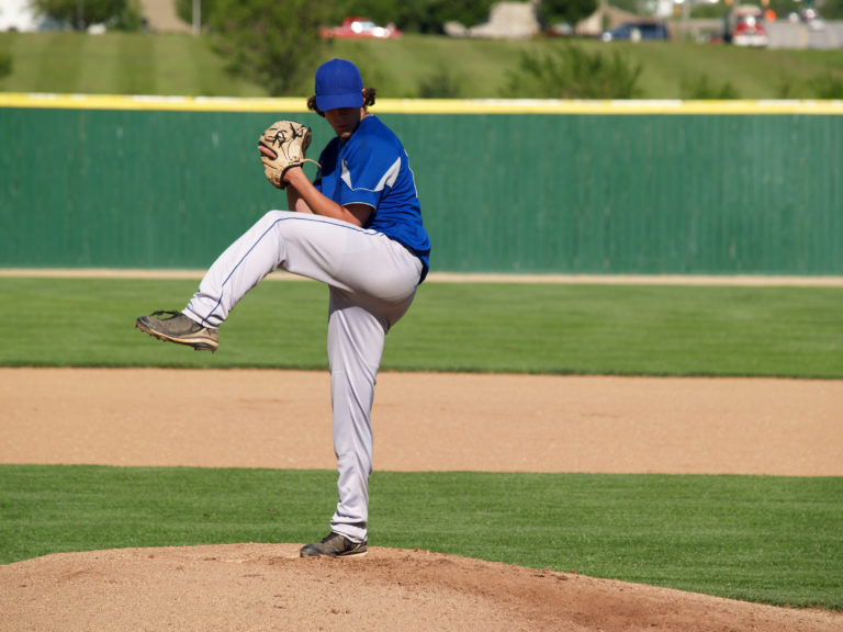 action shot of a high school baseball pitcher winding up to throw the baseball